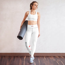 Load image into Gallery viewer, Image of a model holding a rolled yoga mat wearing the iconic premium white leggings with a very sleek and flattering fit and pop of color on the lower leg with the red and black logo design and also the small logo on the waist band.