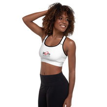 Load image into Gallery viewer, image of a black fitness model wearing the white Red valenteen padded sports bra which has logo center front,  a black trim around the neckline and armhole edges, and contrast stitching. Model has teamed cropped sports bra top with black leggings.