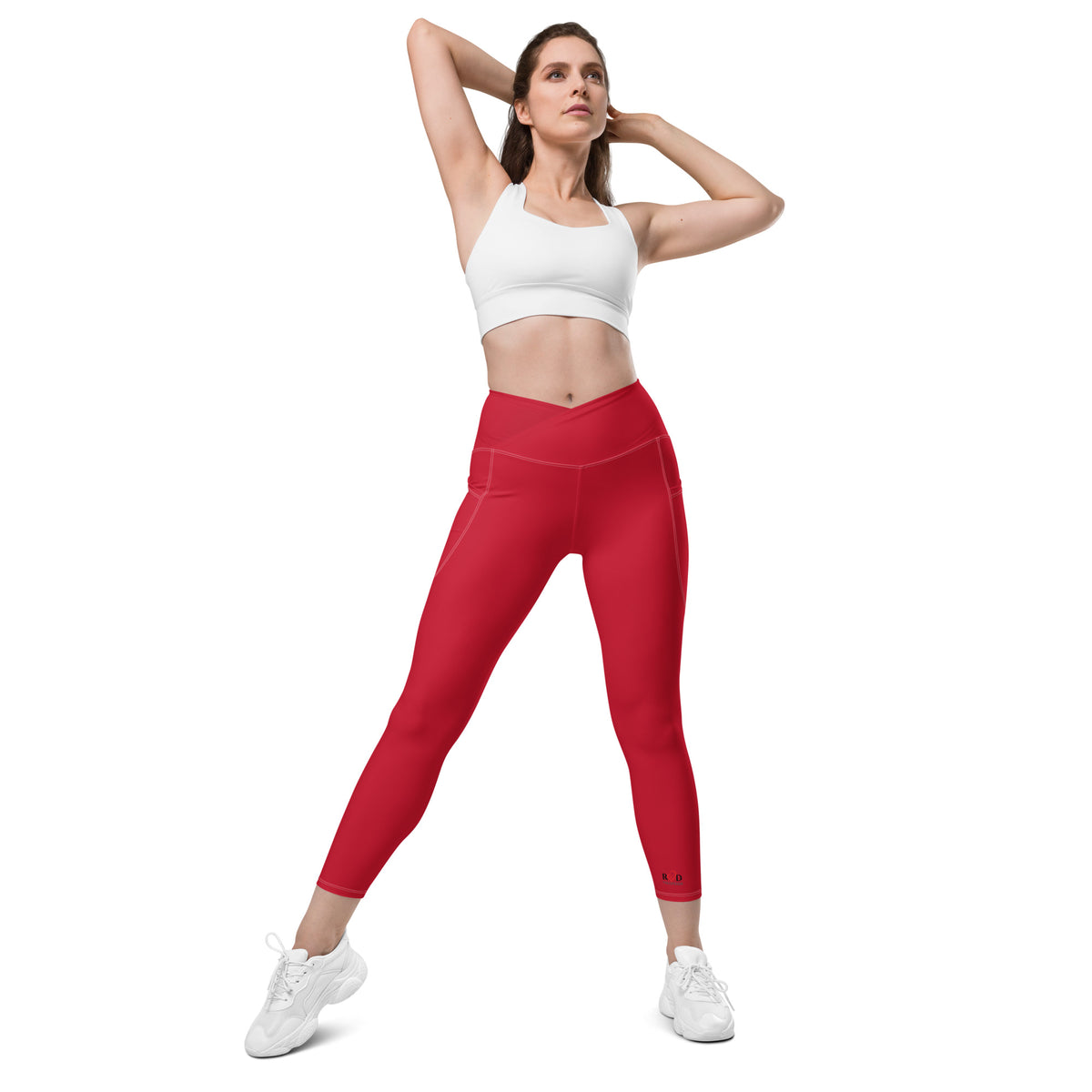 Woman wearing a white sports bra and red leggings on a white background