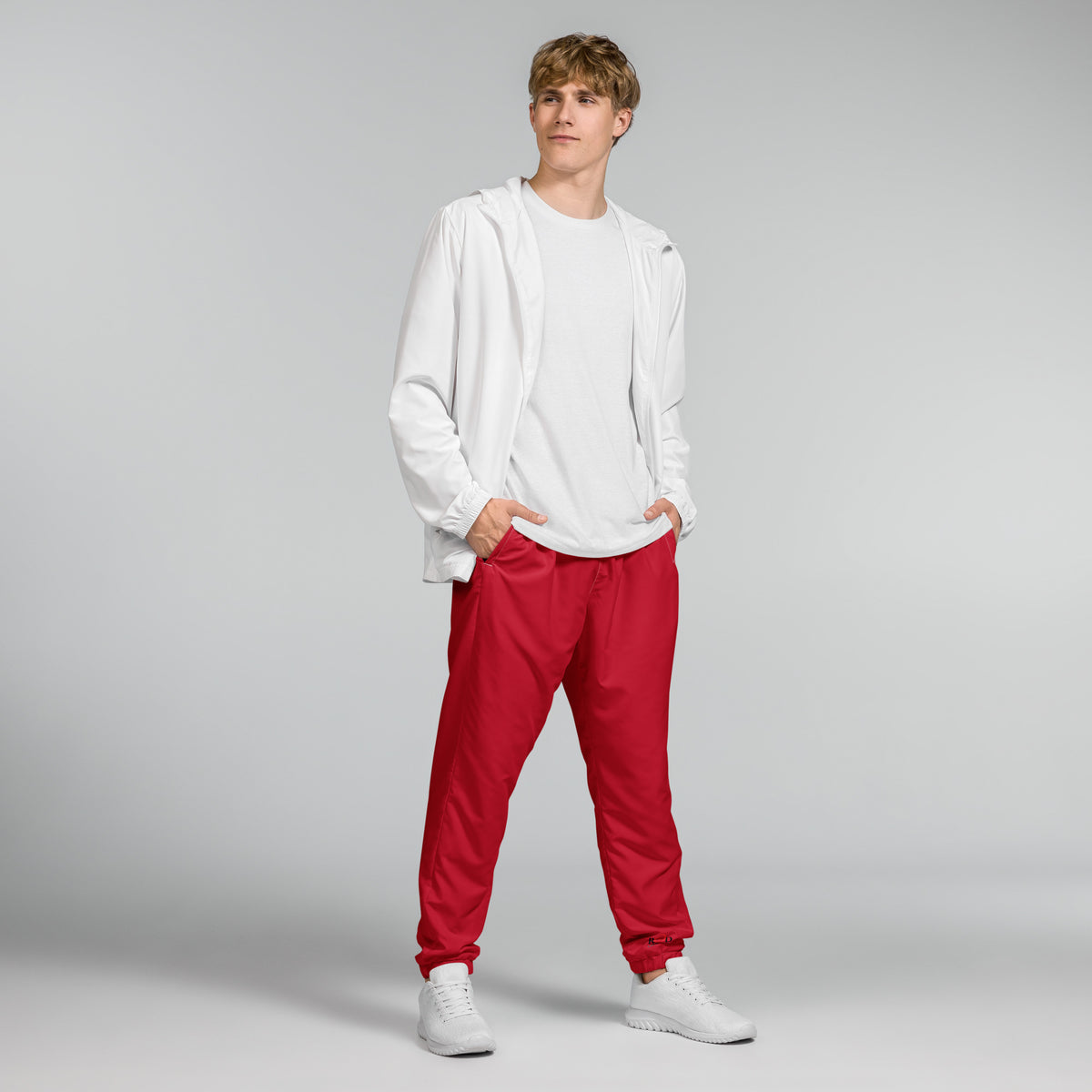 Person wearing a white hoodie and red pants on a gray background