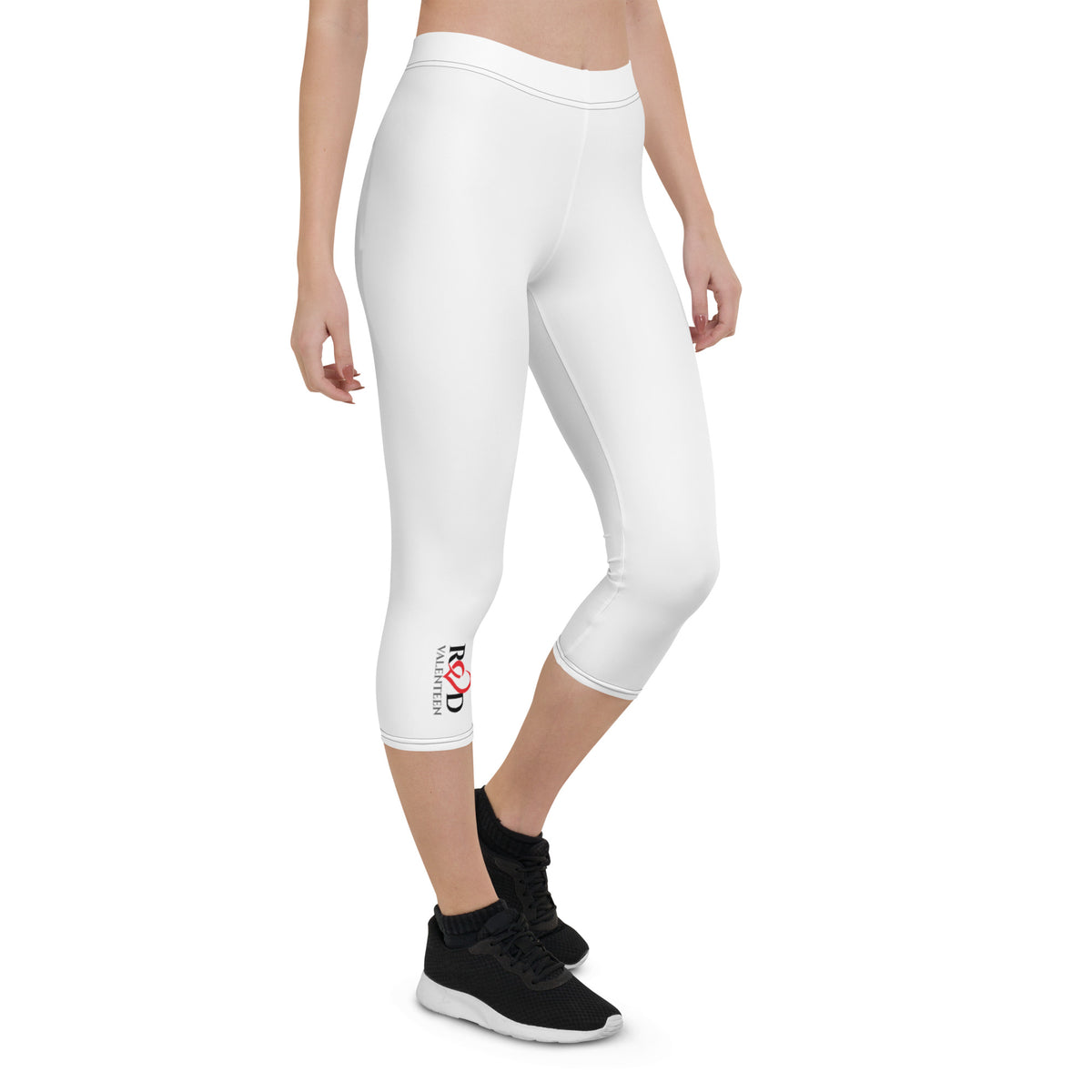 Person wearing white capri leggings with a brand logo Red Valenteen and black sneakers on a white background