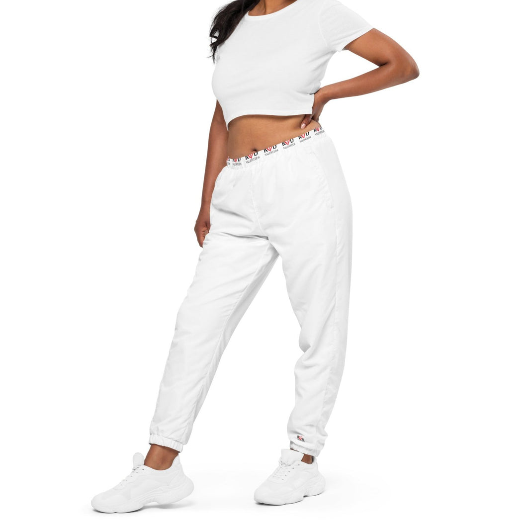 image of a girl posing with her hand on hips wearing white tracksuit pants with Red Valenteen logo waist pattern and matching white sneakers and tshirt.