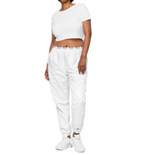 Load image into Gallery viewer, Front view image of a  woman wearing stylish, modern fit white track pants with elastic waist and elastic cuff at ankles, with subtle Red Valenteen logo around the wait and small logo on right ankle. 
